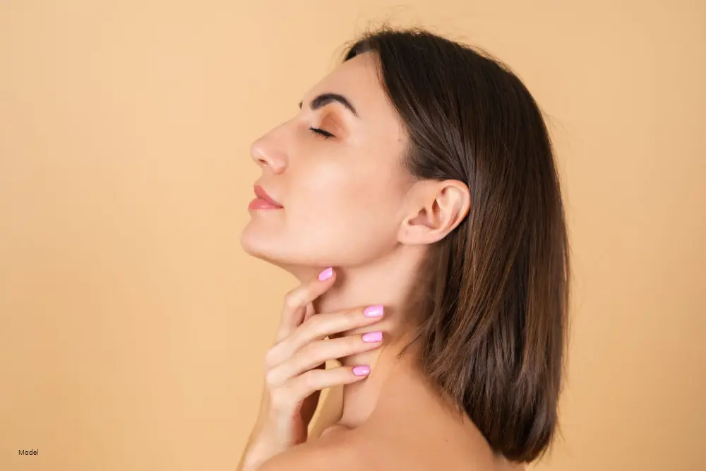Woman showing her side profile and touching her jaw.