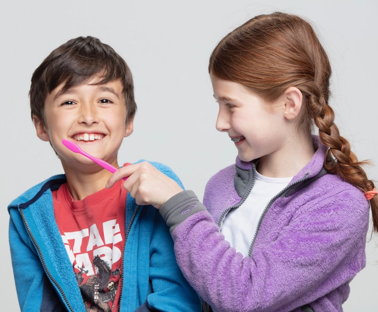 Sibling showing brother how to brush teeth